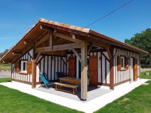 a large wooden cabin with a table and a bench at Pierron in Linxe