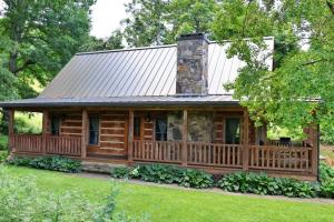 a log cabin with a porch and a stone chimney at The Meadows in Cherokee