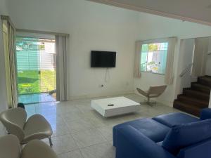 a living room with a blue couch and a tv at Casa de Praia 6 quartos e 4 suítes! in Valença