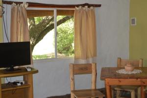 a room with a table and a television and a window at Rancho Escondido in Mina Clavero