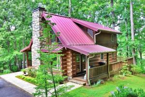 a cabin in the woods with a red roof at The Highland in Cherokee
