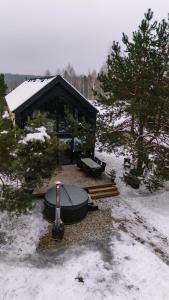 a cabin in the snow with a table and benches at Zakątek Lipowy Most in Lipowy Most
