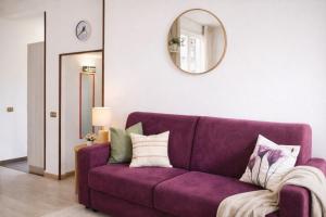 a purple couch in a living room with a mirror at Lake Como Lilla Apartment in Oliveto Lario