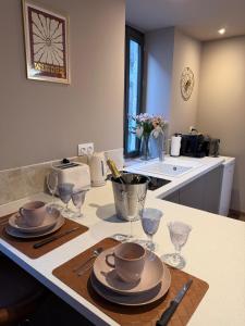 a kitchen counter with plates and wine glasses on it at L'écrin - Studio Cosy et Lumineux in Andance +4 photos
