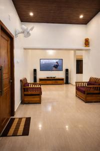 a living room with two couches and a flat screen tv at Mamoksha Riverdale in Padinjarathara