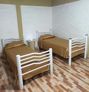 two beds in a room with wooden floors at El Volcán in Tupungato