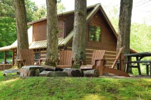 a cabin in the woods with two chairs in front at The Oakes in Cherokee