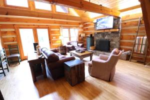 a living room with couches and a television in a log cabin at The Hilltop in Cherokee +24 photos