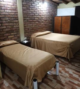 two beds in a room with a brick wall at El Volcán in Tupungato