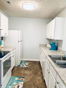 a kitchen with white cabinets and a white refrigerator at Covington Station Escape in Lithonia +5 photos