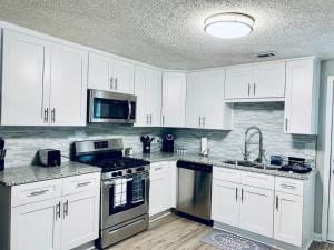 a kitchen with white cabinets and stainless steel appliances at Hartsfield Jackson Escape in College Park