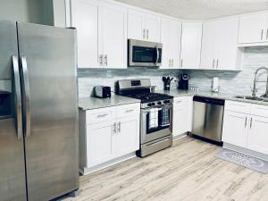 a kitchen with white cabinets and a stainless steel refrigerator at Hartsfield Jackson Escape in College Park +5 photos