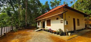 a small house with potted plants in front of it at Mamoksha Riverdale in Padinjarathara