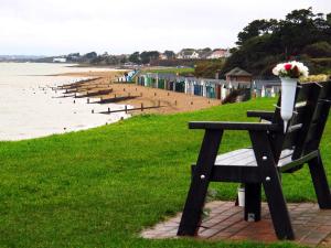 a bench with a bouquet of flowers sitting on top of a beach at Mahe - Lee on the Solent in Lee-on-the-Solent