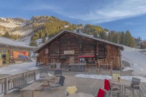 a log building with tables and chairs in front of it at Alpinhotel Bort in Grindelwald
