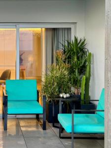 two blue chairs and a table with potted plants at Feel So Good Apartment with Sea View Hot Tub in Sesimbra