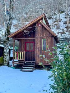 a small cabin with a red door in the snow at Camping el Cares in Santa Maria de Valdeón