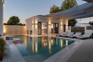 a swimming pool with chairs next to a house at Palm View Suites in Kourouta