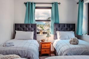 two beds in a bedroom with blue curtains and a window at The Suite at O'Shea's in Killorglin