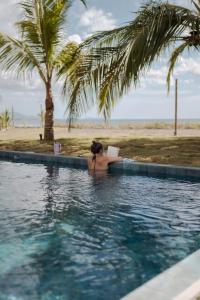 a woman reading a book in a swimming pool next to a beach at Manta Project in Morrillo