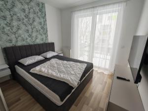 a bedroom with a bed and a large window at Juniper 3 Business in Kecskemét