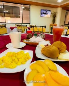 a table with plates of food and fruit on it at Hotel Delfin Rosado in Puyo