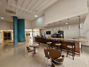 a kitchen with a bar and some chairs and tables at Solar Hotel Luis Eduardo Magalhães in Luís Eduardo Magalhães