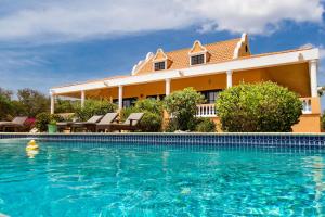 a swimming pool in front of a house at Villa Landhuis 6 - Coral Estate in Willibrordus