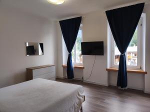 a bedroom with a bed and two windows with blue drapes at La Strada di Tiziano in Pieve di Cadore +15 photos