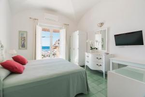 a white bedroom with a bed and a television at Villa La Tartana in Positano