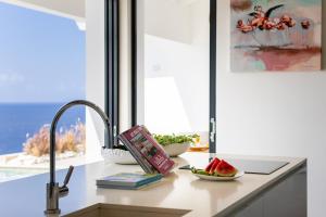 a kitchen counter with a sink with a book and a bowl of watermelon at Villa Esmeraldas 1207 - Coral Estate in Willibrordus
