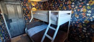 a bedroom with a bunk bed in a room with floral wallpaper at Landhaus Rickies in Aifersdorf