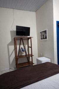 a room with a bed and a television on a shelf at Pousada 2 Rios Comfort in Barra do Garças