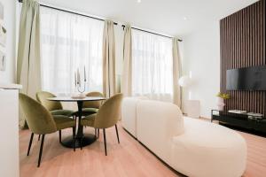 a living room with a white couch and a table and chairs at Appartement en plein centre-ville in Liège