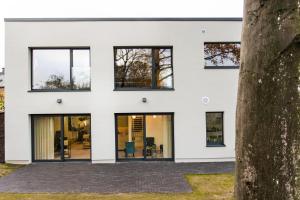 a white house with black windows at Loft La Suite et sa Suite in Thimister