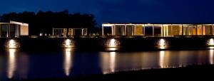 a building with lights on the water at night at Lomas de San Vicente Hotel Boutique in Balneario Buenos Aires