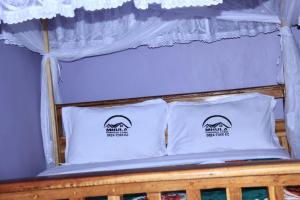 a bed with two white pillows on top of it at Mkula Executive Lodge in Mugumu