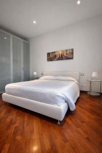 a bedroom with a large white bed and wooden floors at Suite Mazzini in Ravenna