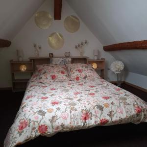 a bedroom with a bed with a floral bedspread at Gite De La Baguelande in Les Andelys