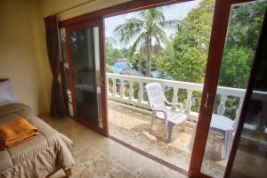a bedroom with a balcony with a bed and a chair at Hugs Guesthouse in Ko Lanta