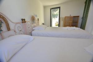 two white beds in a bedroom with a window at Casinha in Sintra