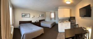 a bedroom with two beds and a kitchen with a table at Yellow Quill Motel in Portage La Prairie