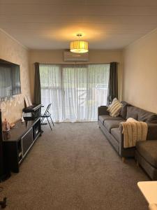 a living room with a couch and a tv at Sochi A double bed Room in a nice home in Upper Hutt