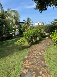 a cobblestone path in a park with palm trees at Maison Baby plein centre in Ambatoloaka