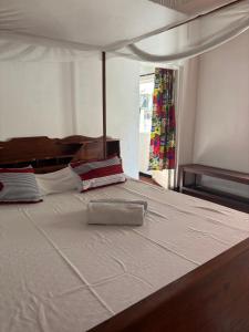 a large white bed with a pillow on it at Maison Baby plein centre in Ambatoloaka