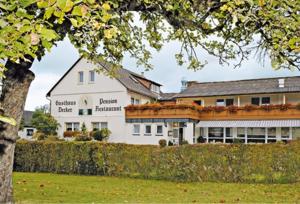 a large white building with a tree in the foreground at Gasthaus Decker in Mittenaar
