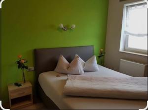 a bedroom with green walls and a bed with white pillows at Gasthaus Decker in Mittenaar