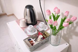 a table with a vase of pink flowers and a tea set at Il Tulipano Camera con bagno privato a Marcianise in Marcianise