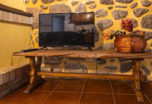 a television on a wooden table with a basket on it at Casa da Ramada in Campo do Gerês