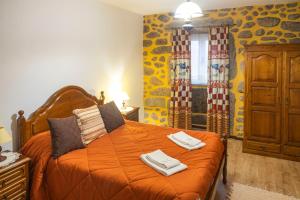 a bedroom with an orange bed with two towels on it at Casa da Ramada in Campo do Gerês